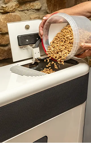persona che riempie una caldaia a biomassa col pellet