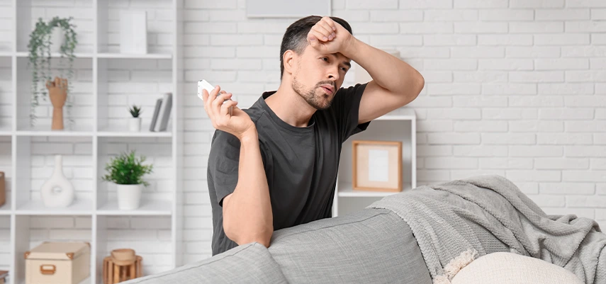 uomo che soffre il caldo e vuole accendere il condizionatore